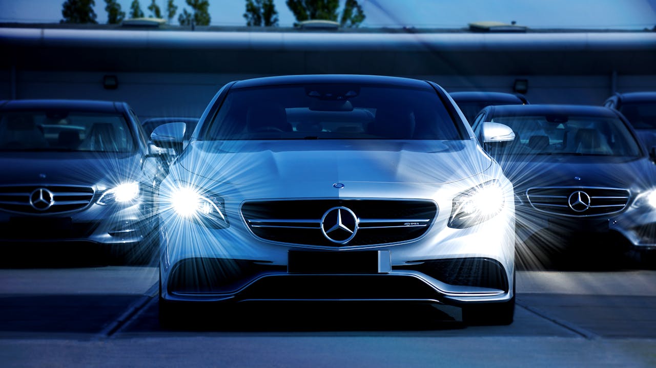 who-we-are-img Front view of a lineup of Mercedes-Benz cars with bright headlights, showcasing luxury and elegance.